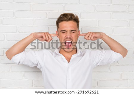 This is too loud! Frustrated man holding fingers in his ears