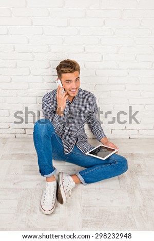 man sitting on the floor with digital tablet and phone