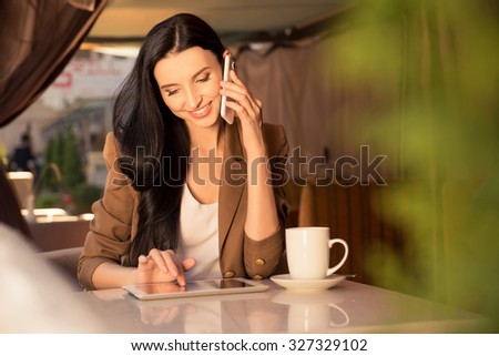 Pretty young business woman in a cafe talking on the phone and work  with tablet