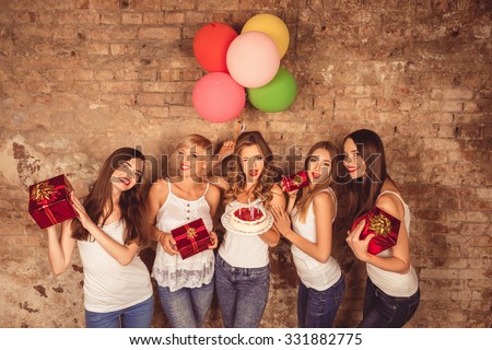 Funny pretty girls holding birthday cake, balloons and presents