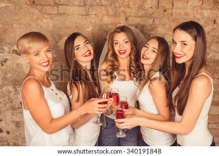 Cute young women wearing dress code celebrating hen-party with sparkling wine