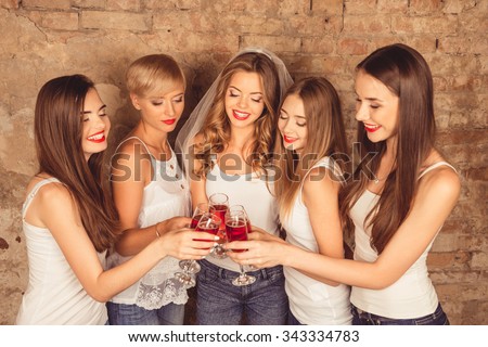 Happy young women wearing dress code celebrating hen-party with sparkling wine