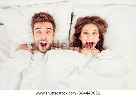 Surprised funny couple in love lying in the bed