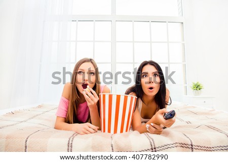 Wow! Two excited girls watching film and eating popcorn