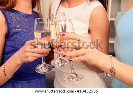 Close up photo of three hands raising glasses with shampagne in a toast
