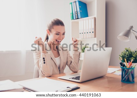 Happy excited successful businesswoman triumphing in office