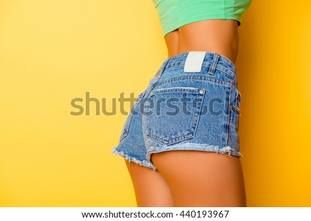 Close up photo of beautiful girl\'s buttocks  wearing jeans on  yellow background