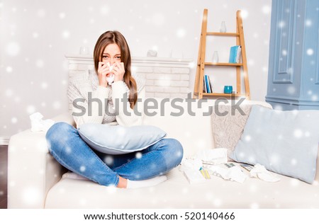 Sick  girl sneezing in tissue sitting on sofa, xmas concept