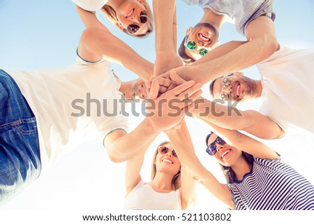 Friends joining hands while standing huddle, down view photo