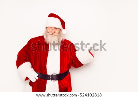 Funny Santa Claus wearing red costume showing something while standing white background