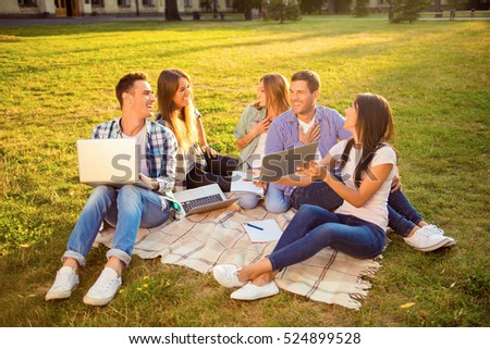 five excited joyful girlfriends and boyfriends  together sitting on blanket and study up.