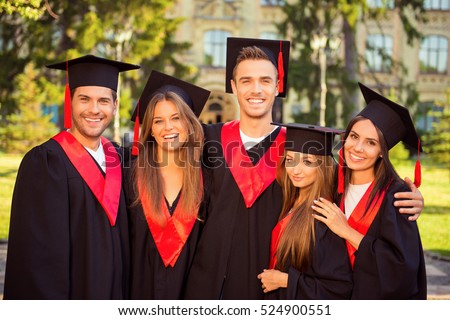 successful joyful five graduates in robes and hats smiling and hugging.