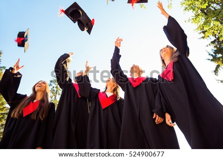 Successful five students with congratulations together throwing graduation hats in the air and celebrating.