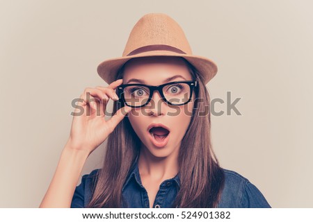 Shocked pretty woman in hat and glasses with open mouth
