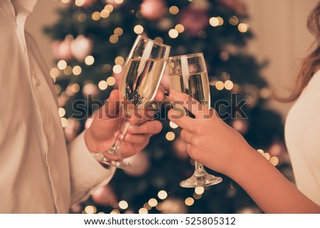 Cheers!Close up photo of two people holding glasses of shampagne on xmas.