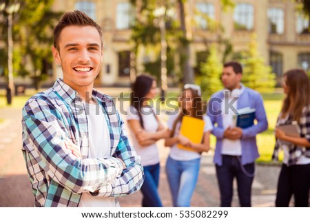 Happy student and crossing hands  while standing on background of university and friends