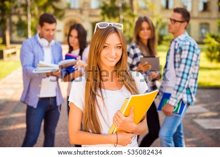 happy cute girl standing near university and holding notebook