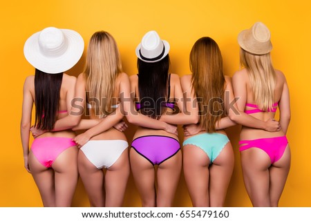 Diet, beauty and healthy bodycare concept. Back view of hot butts and legs of five young ladies, wearing colorful trendy, fashionable swim suits and caps and holding each other`s waist