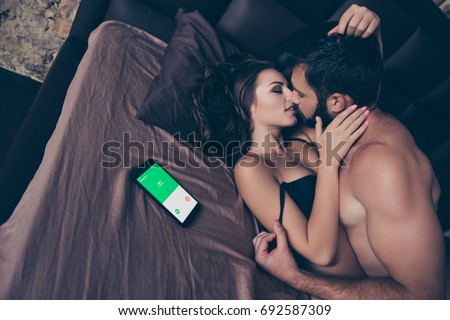 Cheating, controlling, jealous, obsession, possession concept. Wife is calling. Beautiful half naked young couple is making love, so tender, romantic, tempting .Guy is on top, taking off her bra