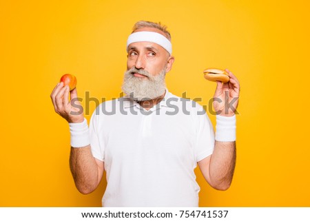 Athlete cool grandpa holds forbidden junkfood cheeseburger and fruit. Weightloss, decision, motivation, healthcare, strength, prohibition, workout, gym, regime, bodycare, calories lifestyle