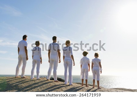 Three generation family in a raw on top of a windy looking at the horizon. Rear view.