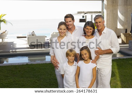 Six person family portrait in the backyard of a luxury house, jumping.
