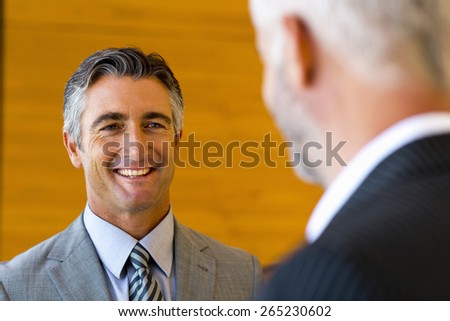 Two smiling executives talking face to face.