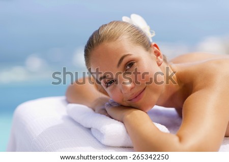 Portrait of young woman bare cheated lying on a massage table.