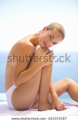 Young blond woman bare cheated, head on knees with hair back.