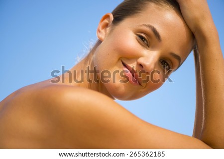 Portrait of beautiful young woman, hands on head.