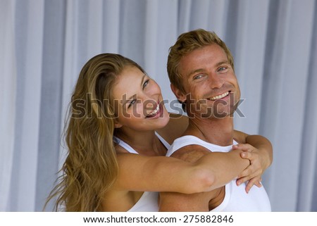 Young blond couple embracing tenderly over  net curtains background,