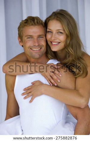 Embracing young couple. The young man is carrying the young girl on his back.