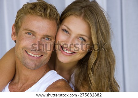 Young blond couple embracing tenderly over  net curtains background,