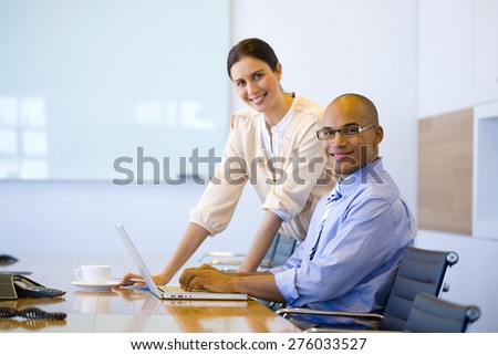 Male and female executives working together in a meeting room.