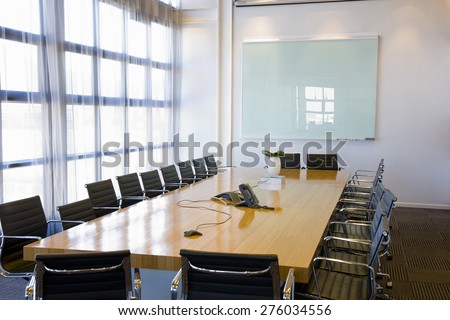 Large view of a meeting room with white board, meeting table and chairs.