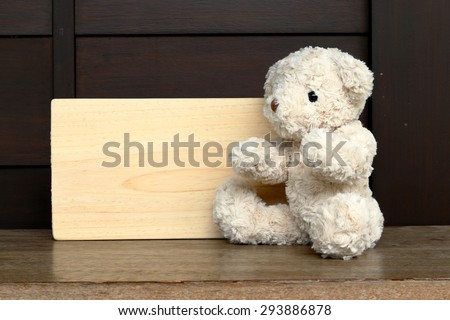 Single teddy bear on a grass and board wood for your text.