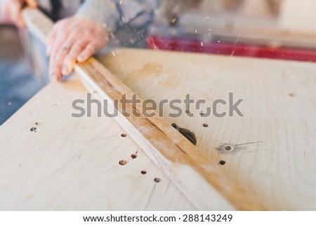 Carpenter in a workshop shaving a wooden deck on a router table. Lots of wood flinders fly away. Unrecognizable. Selective focus