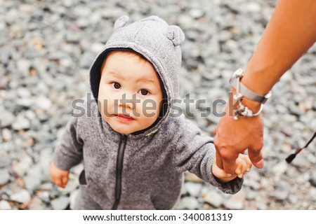 Son in bear costume holding his mother\'s hand and following her. Lifestyle shot from overhead top view. Boy looking at camera
