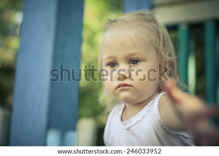 Adorable toddler girl playing in the park. Blurry arm shows in camera.