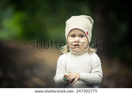 Adorable toddler girl lost in the forest. Autumn. Background forest.