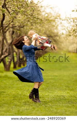 Mom spinning with adorable toddle daughter.  Long wavy black hair. Summer sunny day