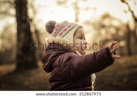 Adorable toddler running forward in the park. Cold spring. Warm colors.
