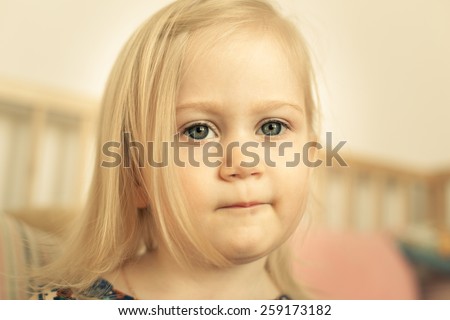 Adorable little girl in her room. Thoughtful, pensive face.