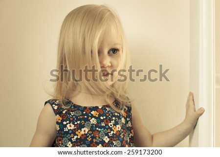 Adorable little girl in her room. Thoughtful, pensive face. The face is covered with long hair
