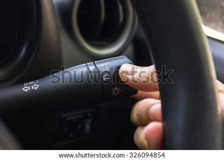 man hand use the signal switch. Car interior detail with worm light.