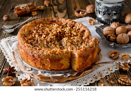 Piece of apple pie with walnut and sugar glaze on a wooden table