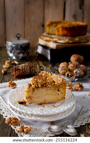Piece of apple pie with walnut and sugar glaze on a wooden table
