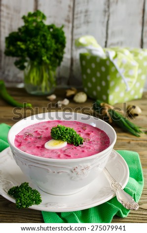 Cold beet soup with egg, cucumber, potatoes and greens on the wooden table. Speciality for hot days. Shallow depth of field, selective focus