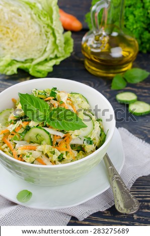 Cabbage salad with cucumber and carrots. Salad and vegetables on wooden table