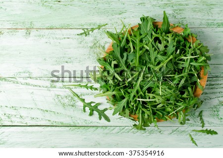 Fresh green arugula in bowl on wooden table. Arugula is rich in vitamins and trace elements